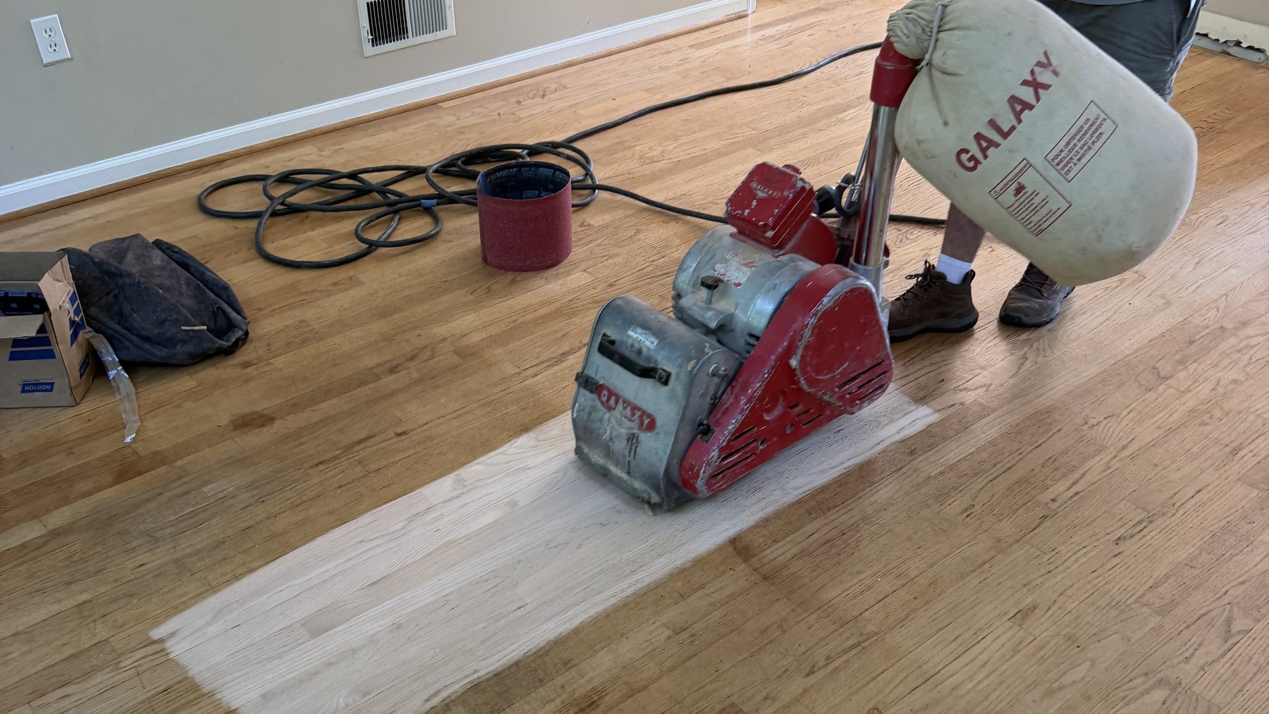 Drum sander revealing bare oak beneath an old finish on a York, PA hardwood floor