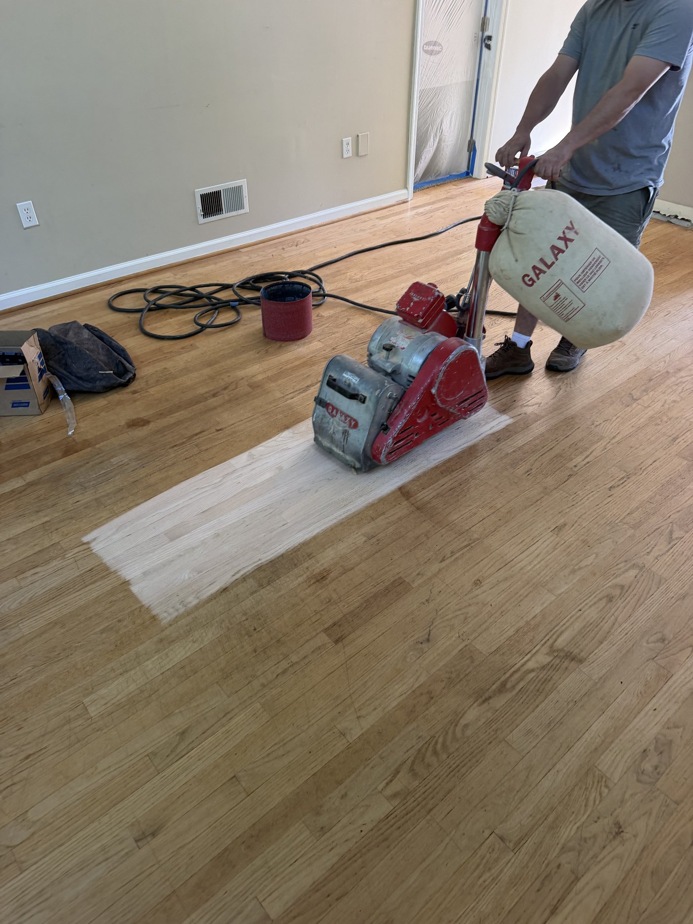 Drum sanding a hardwood floor in York, PA, bare oak emerging beside the old finish